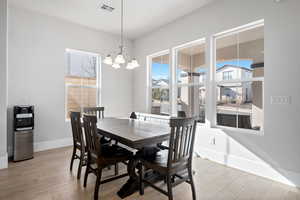 Dining space with plenty of natural light, light wood-type flooring, and a notable chandelier