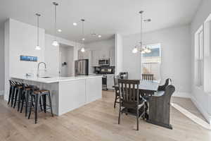 Kitchen featuring hanging light fixtures, decorative backsplash, light hardwood / wood-style floors, kitchen peninsula, and stainless steel appliances