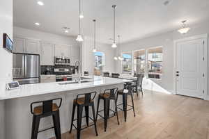 Kitchen with a breakfast bar, pendant lighting, stainless steel appliances, and a spacious island