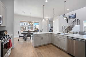 Kitchen featuring an inviting chandelier, sink, appliances with stainless steel finishes, decorative light fixtures, and light hardwood / wood-style floors