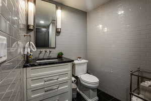 Bathroom with vanity, toilet, and tile walls