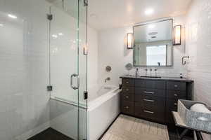 Bathroom with tile patterned flooring, vanity, tile walls, and plus walk in shower