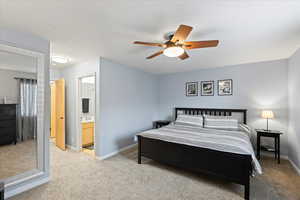 Bedroom featuring ensuite bathroom, ceiling fan, and light carpet