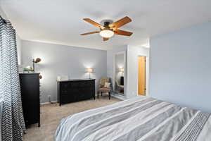 Bedroom with ceiling fan and light colored carpet