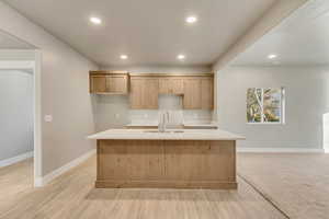 Open kitchen with wood cabinetry, two tone paint, lot of lighting, and quartz countertops.