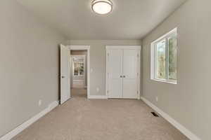 Unfurnished bedroom featuring light colored carpet and a closet