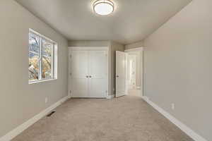 Unfurnished bedroom featuring light carpet and a closet