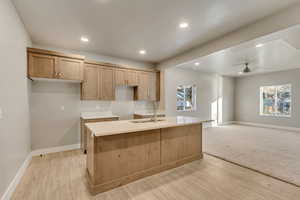 Kitchen with large island, sink, light countertops, and lots of light