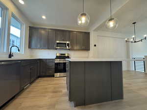 Kitchen with pendant lighting, a kitchen island, sink, and stainless steel appliances