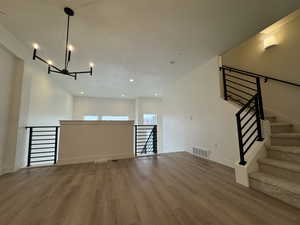 Unfurnished living room featuring hardwood / wood-style floors and an inviting chandelier