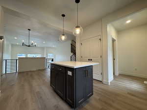 Kitchen featuring light hardwood / wood-style flooring, a kitchen island, and decorative light fixtures