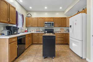Kitchen featuring a center island, light tile patterned floors, black appliances, and sink