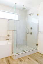 Bathroom featuring wood-type flooring and shower with separate bathtub