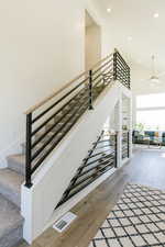 Staircase with ceiling fan, hardwood / wood-style floors, and a high ceiling