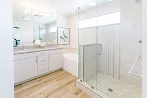 Bathroom with vanity, shower with separate bathtub, and hardwood / wood-style flooring