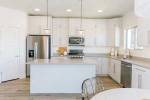 Kitchen with pendant lighting, white cabinetry, sink, and appliances with stainless steel finishes