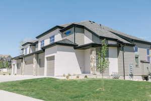 View of side of home with a garage and a lawn