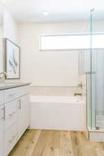 Bathroom featuring hardwood / wood-style floors, vanity, and shower with separate bathtub