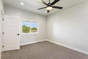 Carpeted spare room featuring ceiling fan