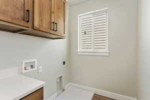 Laundry area featuring hookup for an electric dryer, gas dryer hookup, cabinets, and washer hookup