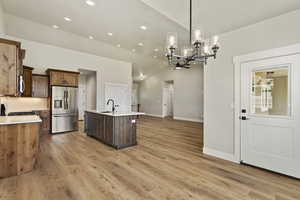 Kitchen featuring appliances with stainless steel finishes, sink, a chandelier, hanging light fixtures, and an island with sink