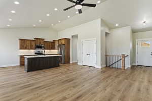 Kitchen featuring a kitchen island with sink, high vaulted ceiling, light hardwood / wood-style flooring, ceiling fan, and appliances with stainless steel finishes