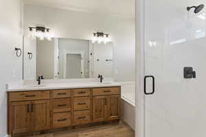 Bathroom with hardwood / wood-style flooring, vanity, and separate shower and tub