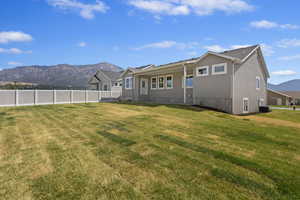 Back of property with a mountain view, a yard, and central air condition unit