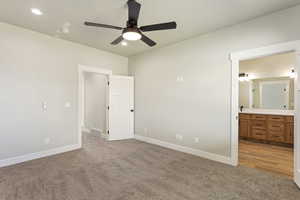 Unfurnished bedroom with carpet floors, ensuite bath, and ceiling fan