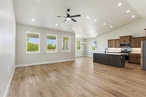 Kitchen with sink, stainless steel appliances, an island with sink, light hardwood / wood-style floors, and ceiling fan with notable chandelier