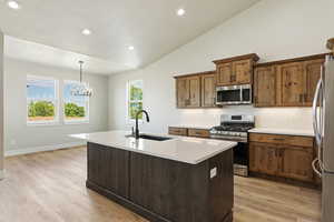 Kitchen with hanging light fixtures, a kitchen island with sink, sink, and stainless steel appliances