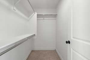 Walk in closet featuring light colored carpet