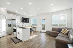 Kitchen with appliances with stainless steel finishes, sink, a center island with sink, light hardwood / wood-style flooring, and white cabinetry