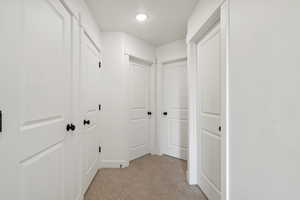 Corridor featuring light carpet and a textured ceiling