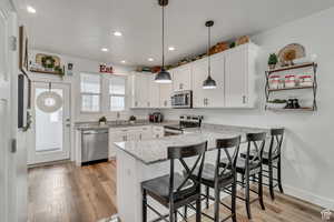 Kitchen featuring decorative light fixtures, white cabinetry, and appliances with stainless steel finishes