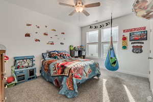 Bedroom with ceiling fan, carpet floors, and a textured ceiling