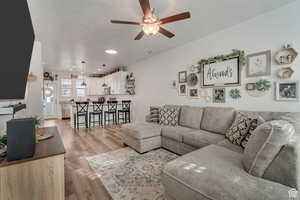 Living room with a textured ceiling, light hardwood / wood-style floors, and ceiling fan