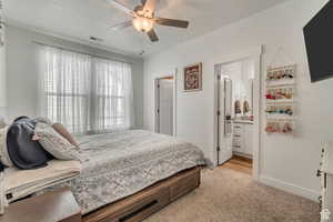 Carpeted bedroom featuring ceiling fan, a textured ceiling, and ensuite bath