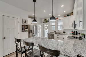 Kitchen featuring kitchen peninsula, appliances with stainless steel finishes, and white cabinetry