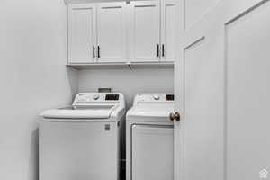 Washroom featuring cabinets and washing machine and dryer