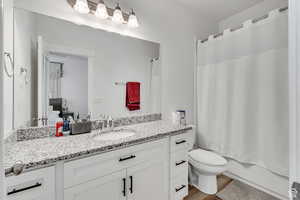 Full bathroom featuring wood-type flooring, vanity, toilet, and shower / bathtub combination with curtain