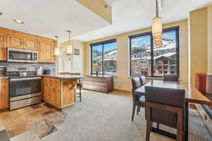 Kitchen with tasteful backsplash, kitchen peninsula, pendant lighting, a breakfast bar, and appliances with stainless steel finishes