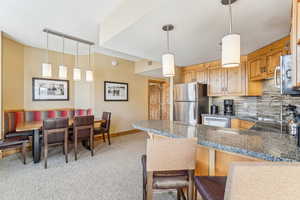 Kitchen with kitchen peninsula, appliances with stainless steel finishes, backsplash, sink, and a breakfast bar area