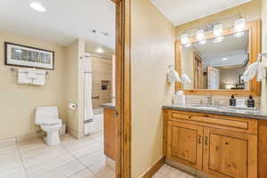 Full bathroom with tile patterned flooring, shower / bath combination with curtain, toilet, and vanity