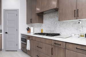 Kitchen featuring decorative backsplash, stainless steel gas cooktop, and custom exhaust hood