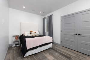 Bedroom with dark hardwood / wood-style floors and a closet