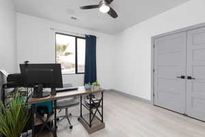 Home office with light hardwood / wood-style floors and ceiling fan