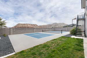 View of tennis court with a mountain view, basketball court, and a lawn