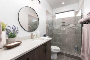 Bathroom featuring an enclosed shower, vanity, toilet, and tile patterned floors