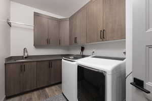 Washroom featuring cabinets, a textured ceiling, dark wood-type flooring, sink, and washing machine and clothes dryer